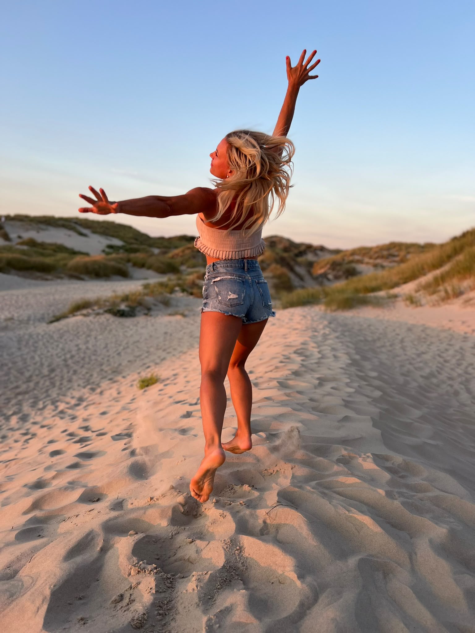 Nicole springt in den Dünen bei Sonnenuntergang